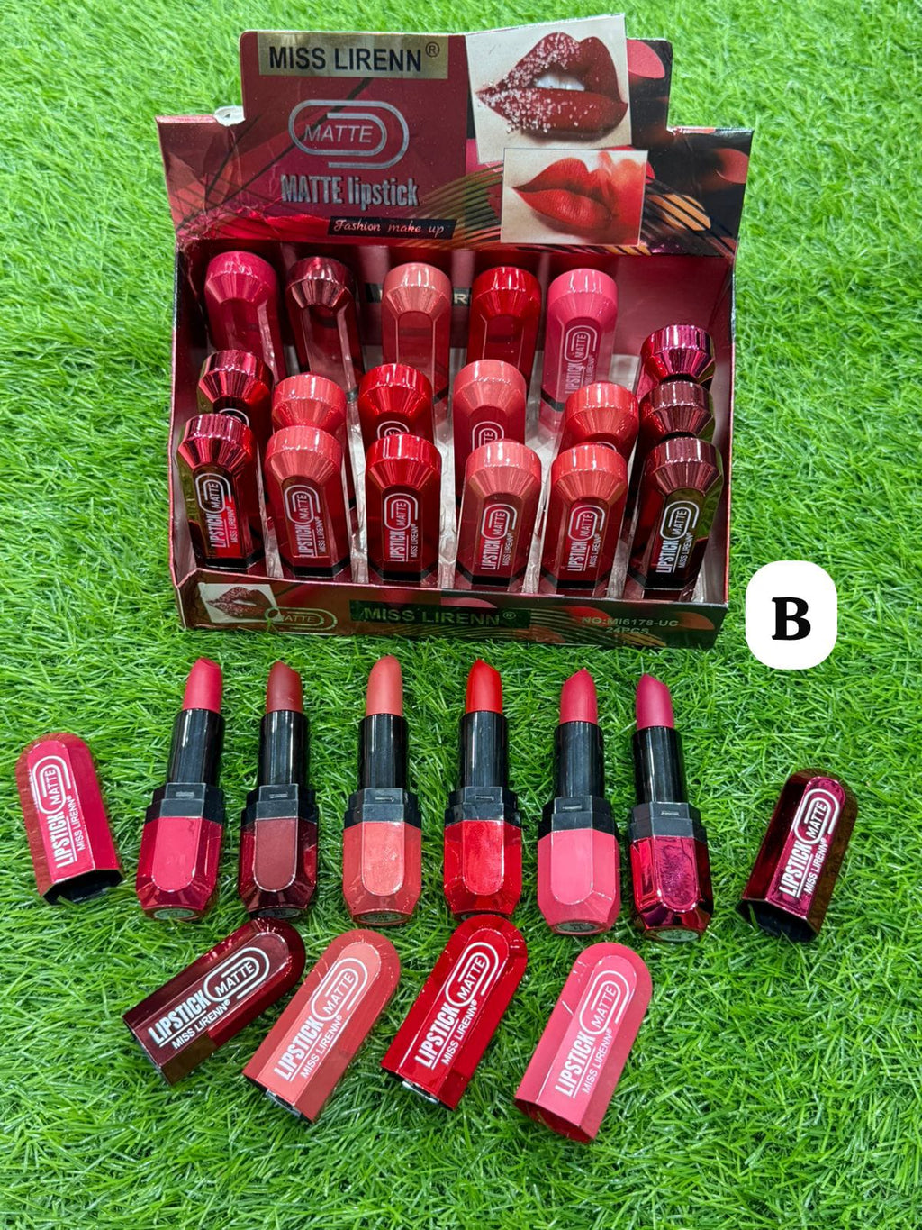 Box of Miss Liren lipsticks with multiple lipsticks displayed in front on a grass background