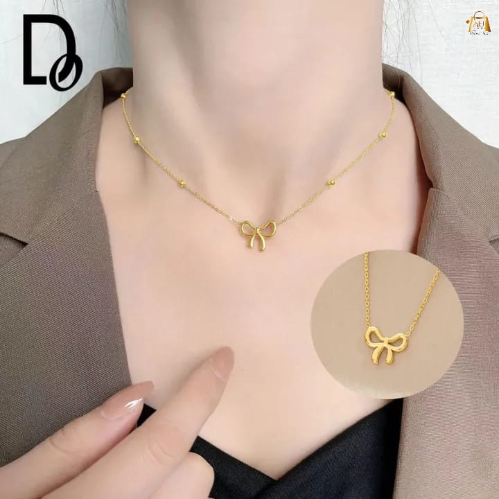 Gold necklace with a bow pendant on a mannequin, with a close-up inset showing the pendant.