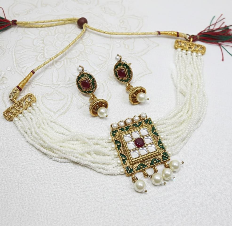 Jewelry set with necklace, earrings, and decorative piece on a white background