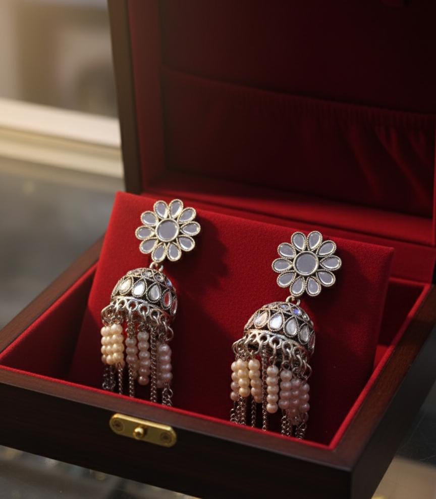 Pair of floral earrings with pearl and gemstone details in a red jewelry box.