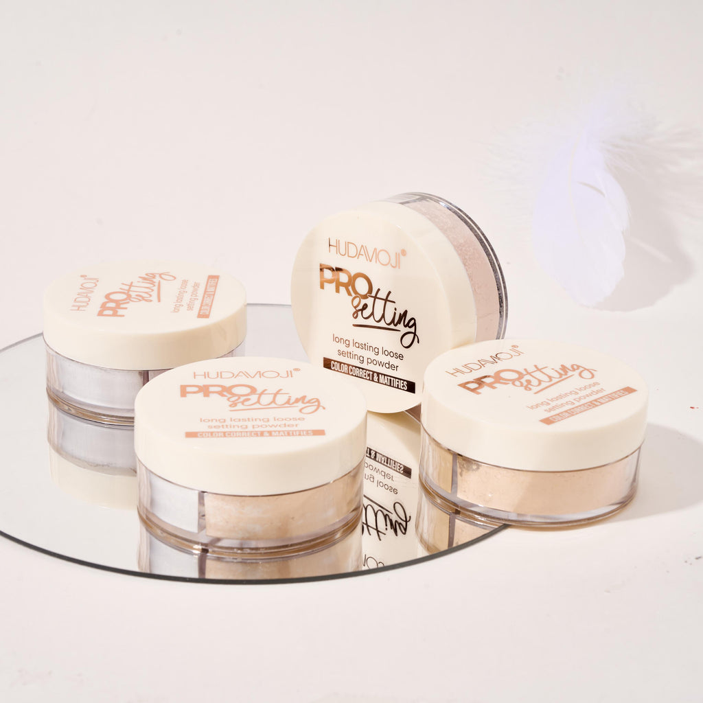Set of Huda Beauty Pro setting powders on a reflective surface with a white background