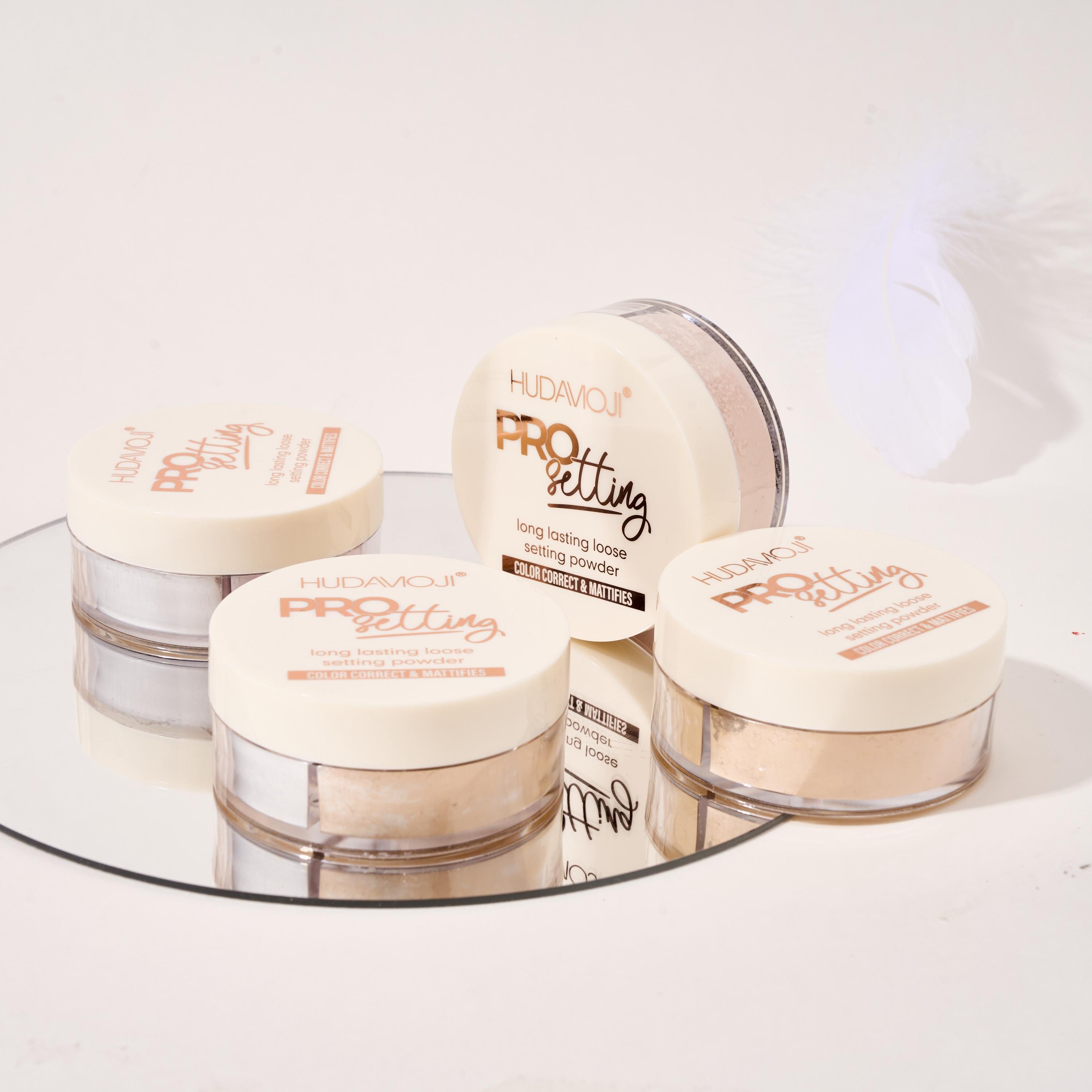 Set of Huda Beauty Pro setting powders on a reflective surface with a white background